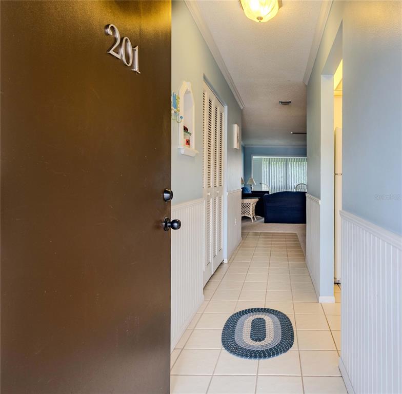 An open door reveals a tiled entryway leading into a living area with blue walls — 1640 STICKNEY POINT ROAD UNIT 201, SARASOTA, FL