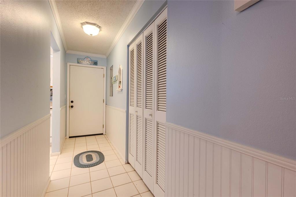 A hallway features white louvered closet doors, beadboard wainscoting, and light-colored tile flooring — 1640 STICKNEY POINT ROAD UNIT 201, SARASOTA, FL