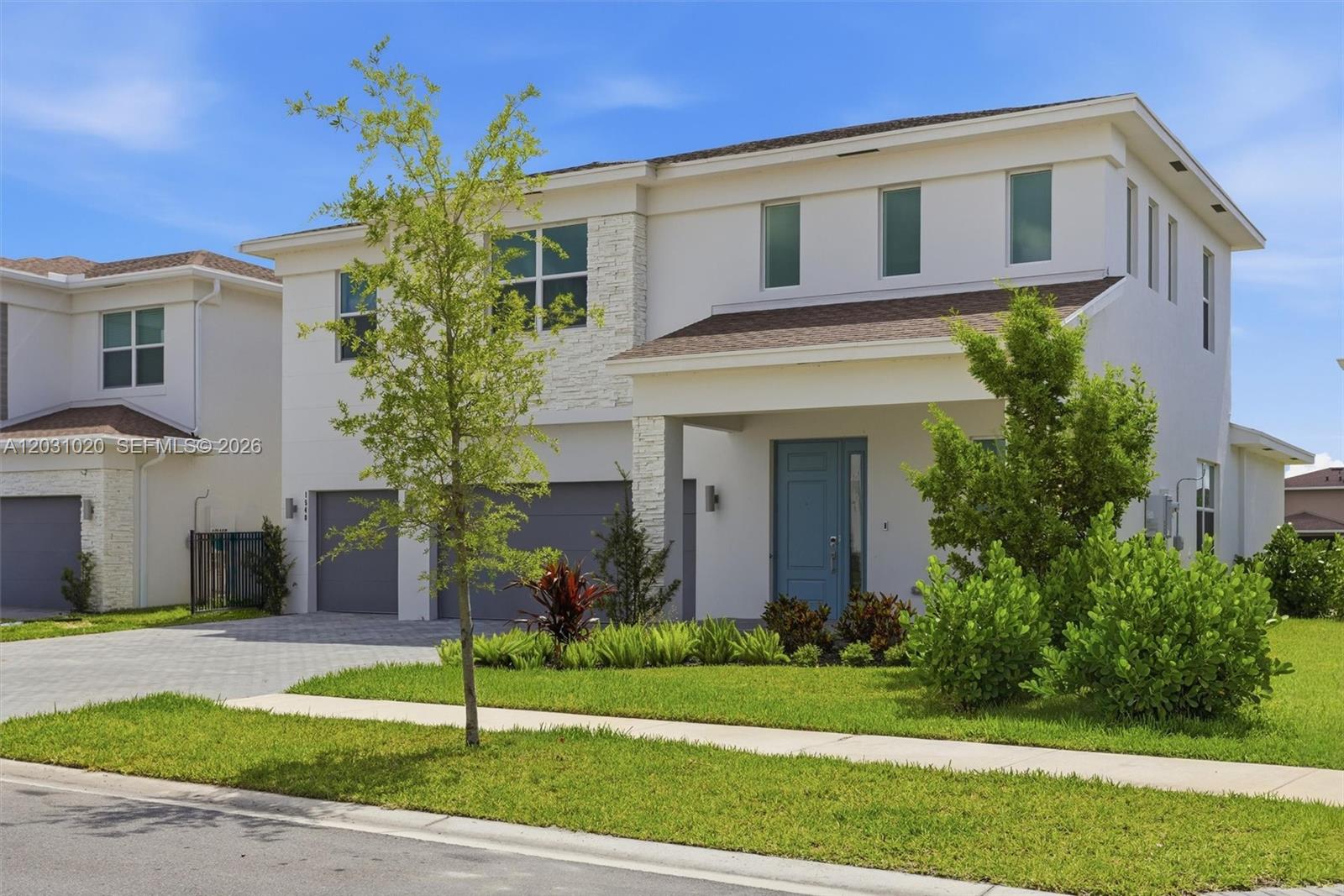 A two-story white house features a blue front door, a two-car garage, and landscaping — 1548 Stockbridge St, Loxahatchee FL 33470, LOXAHATCHEE, FL