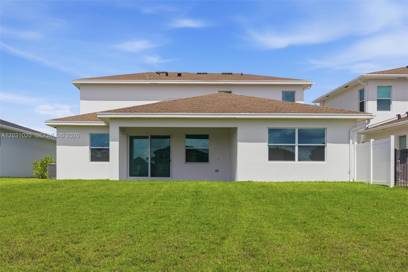 The exterior rear view of a two-story house features a covered patio and lawn — 1548 Stockbridge St, Loxahatchee FL 33470, LOXAHATCHEE, FL