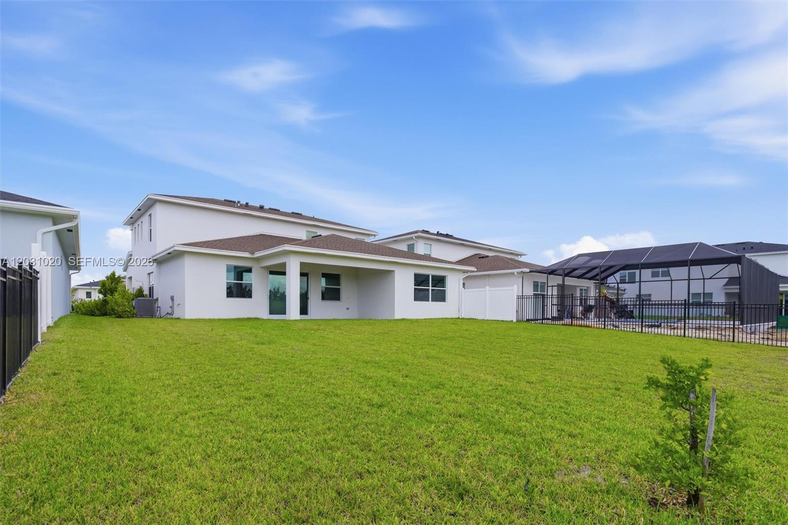 The backyard features a grassy lawn, a covered patio, and a fenced pool enclosure — 1548 Stockbridge St, Loxahatchee FL 33470, LOXAHATCHEE, FL