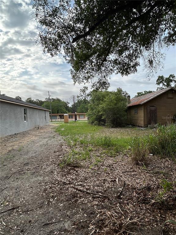 An outdoor view shows a dirt path between a gray building and a brown shed — PALMETTO STREET, EUSTIS, FL