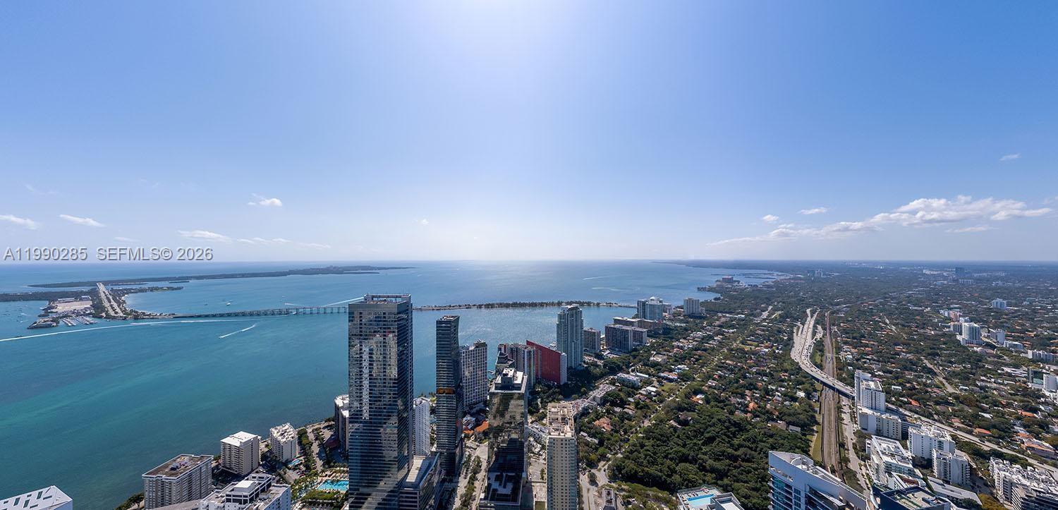 An aerial view shows a coastal city skyline with high-rise buildings and a bridge — 1210 Brickell Ave # 7001, Miami FL 33131, MIAMI, FL