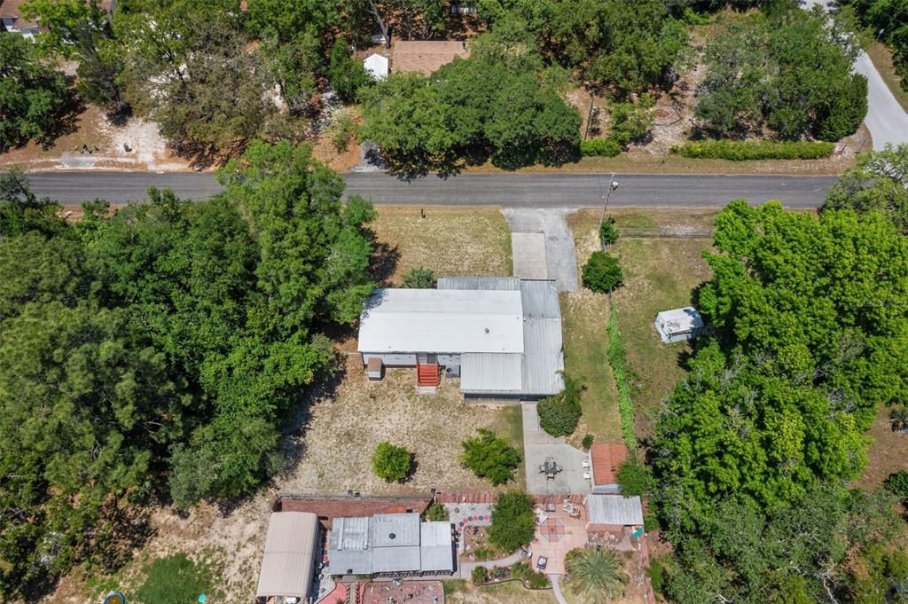 An aerial view shows a house with a metal roof, a driveway, and surrounding trees — 7510 W OTTER STREET, HOMOSASSA, FL