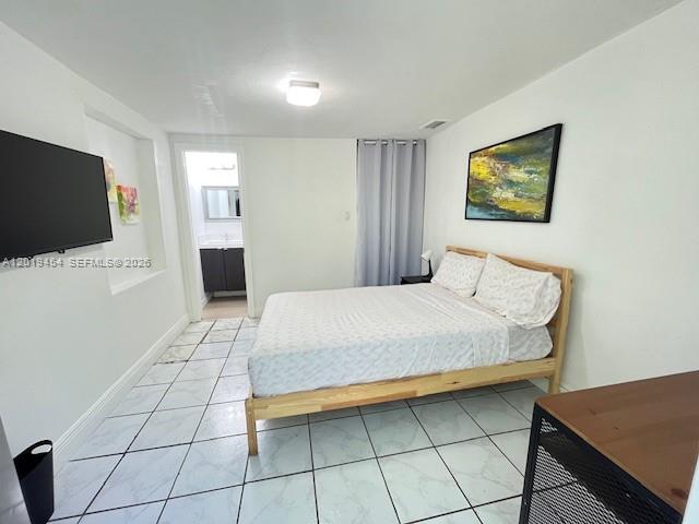 A bedroom features a bed, a wall-mounted television, and tiled flooring — 410 NW 31st St # 2, Miami FL 33127, MIAMI, FL