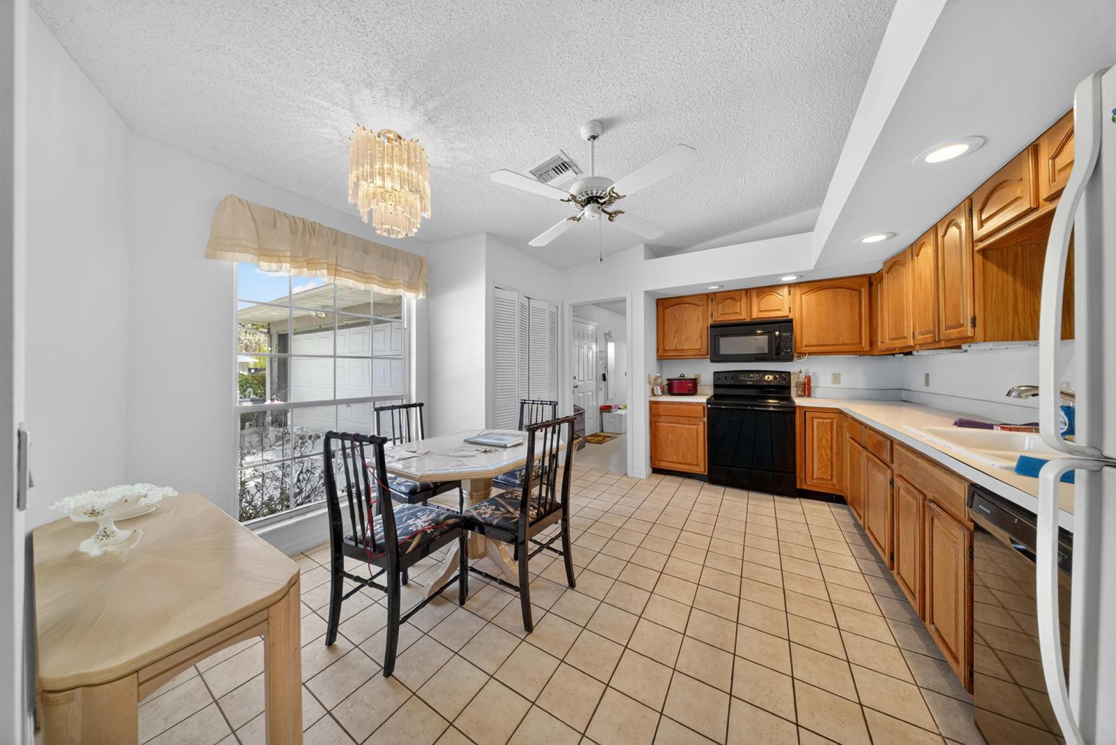 A kitchen and dining area with wood cabinets, tile flooring, and a crystal chandelier — 5110 Eagle Drive, Fort Pierce FL 34951, FORT PIERCE, FL