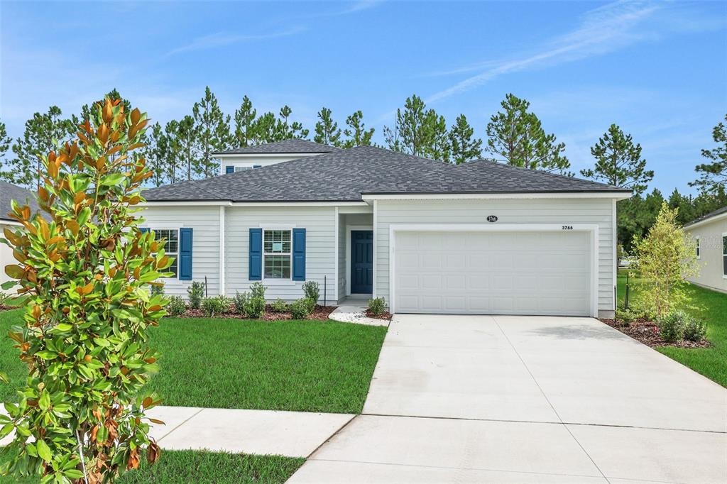 A single-story house with light siding, blue shutters, a two-car garage, and a front lawn — 3766 HOLSTEIN WAY, GREEN COVE SPRINGS, FL