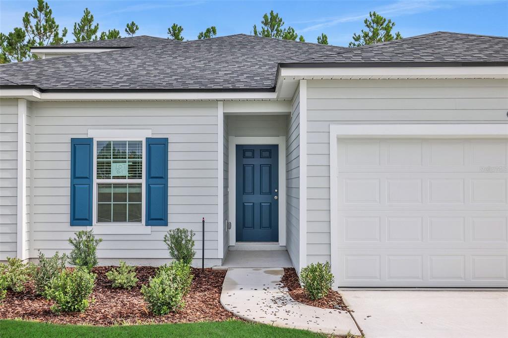 A single-story house exterior features light gray horizontal siding, a blue front door, and shutters — 3766 HOLSTEIN WAY, GREEN COVE SPRINGS, FL