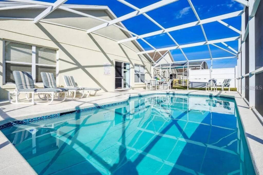 A swimming pool with a screened-in enclosure and lounge chairs on a concrete patio — 160 BLOOMINGDALE DRIVE, DAVENPORT, FL