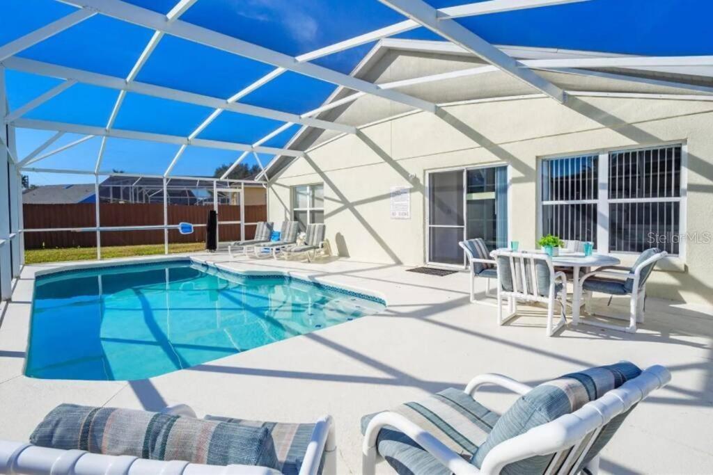 A screened-in patio features a swimming pool, outdoor dining furniture, and lounge chairs — 160 BLOOMINGDALE DRIVE, DAVENPORT, FL