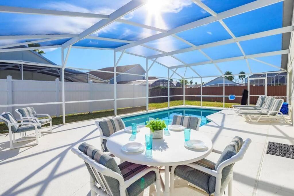 A screened-in patio features a dining set, lounge chairs, and a swimming pool — 160 BLOOMINGDALE DRIVE, DAVENPORT, FL
