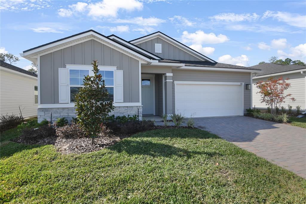 A single-story house features gray siding, a stone veneer base, and a two-car garage — 200 ENCLAVE AVENUE, PALM COAST, FL