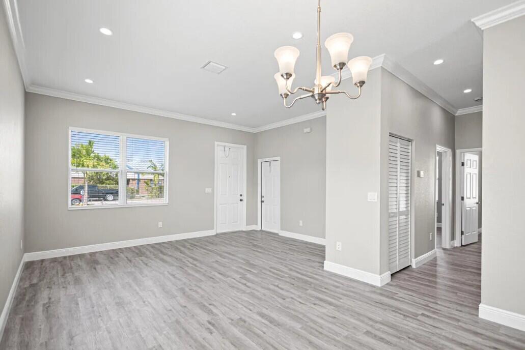 An empty room with gray walls, wood-look flooring, a chandelier, and a white front door — 132 NW 11th Avenue, Boynton Beach FL 33435, BOYNTON BEACH, FL