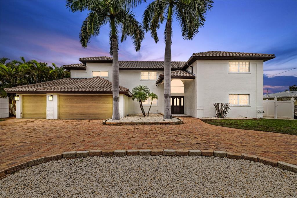 A two-story white house with a brick driveway, palm trees, and a multi-car garage — 423 55TH AVENUE, ST PETE BEACH, FL