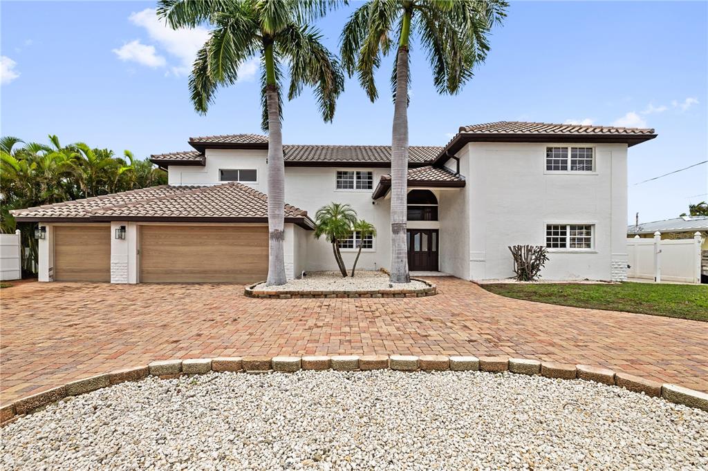 A two-story white house with a tile roof, brick driveway, and two tall palm trees — 423 55TH AVENUE, ST PETE BEACH, FL