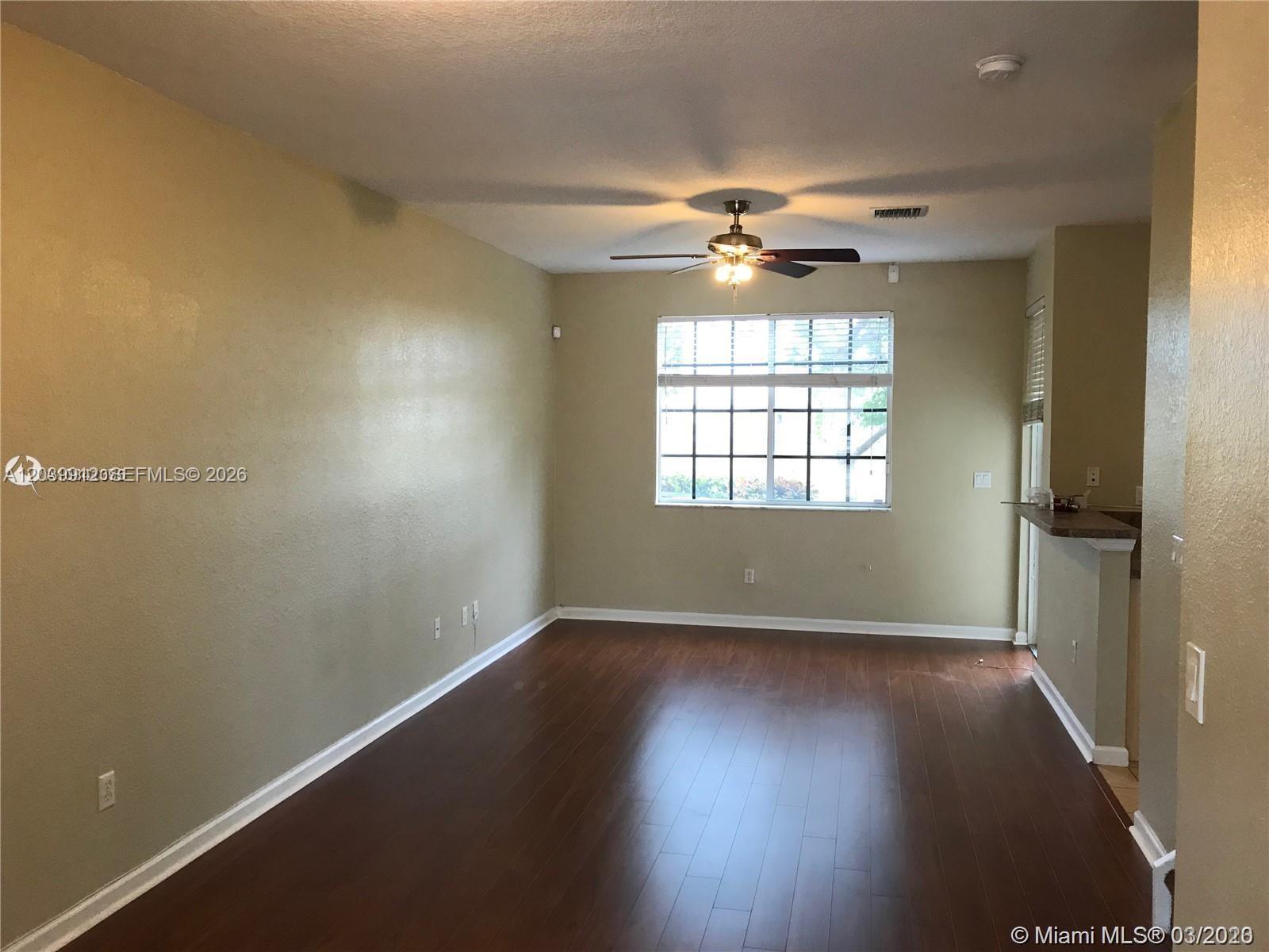An empty room features dark wood flooring, tan walls, and a ceiling fan — 1413 Lucaya Dr, Riviera Beach FL 33404, RIVIERA BEACH, FL