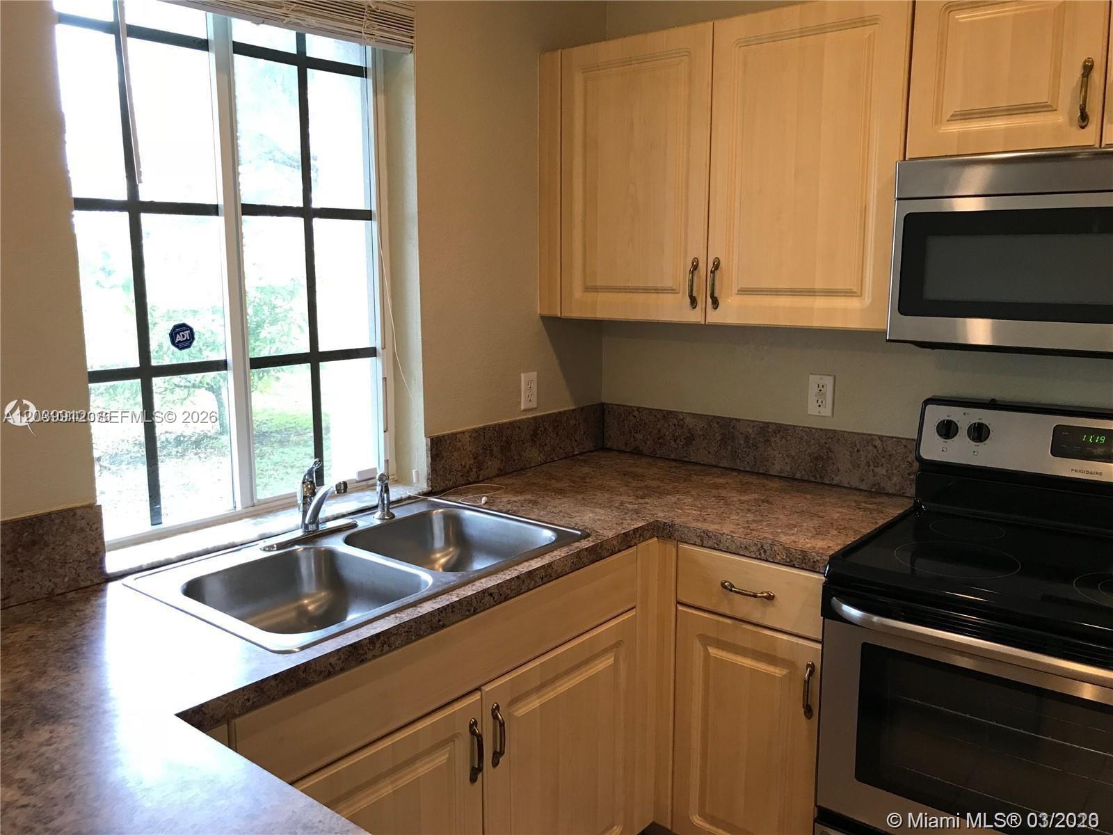 A kitchen features light wood cabinets, a double sink, and a stainless steel oven — 1413 Lucaya Dr, Riviera Beach FL 33404, RIVIERA BEACH, FL
