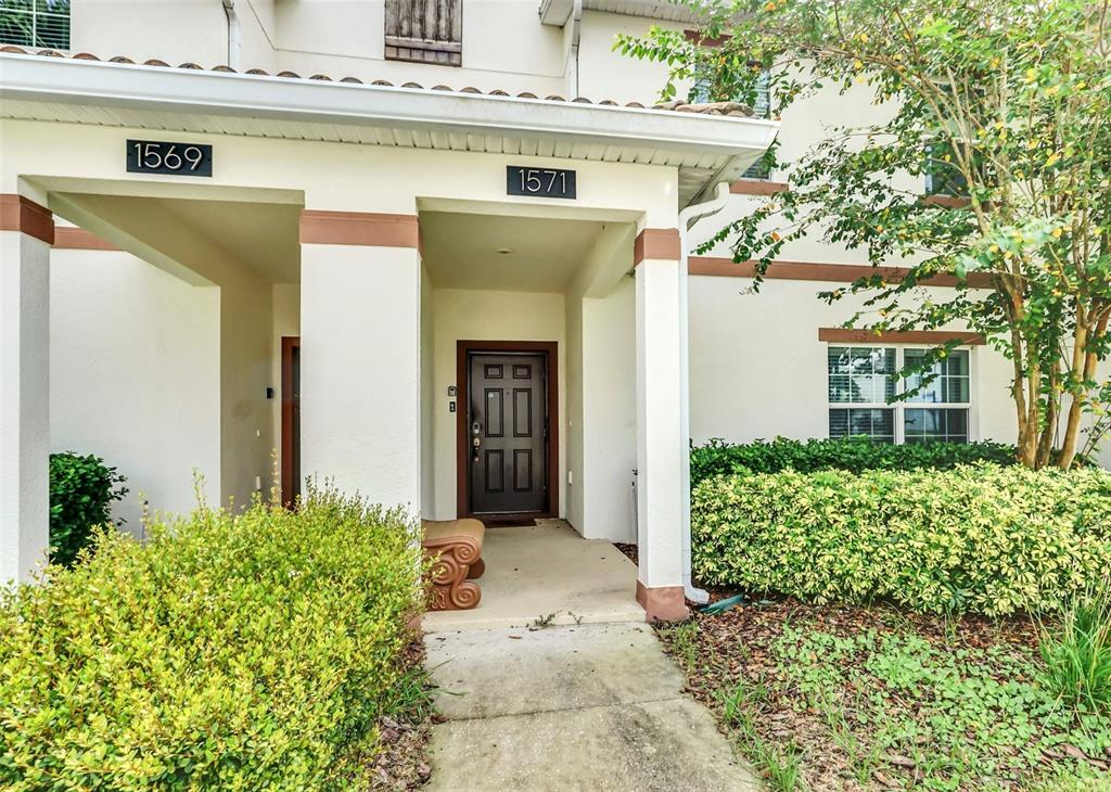 The exterior of a two-story building shows two unit entrances with house numbers 1569 and 1571 — 1571 PLUNKER DRIVE, DAVENPORT, FL