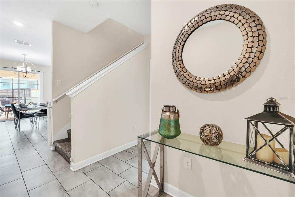 A glass console table with decor sits in a foyer next to a carpeted staircase — 1571 PLUNKER DRIVE, DAVENPORT, FL