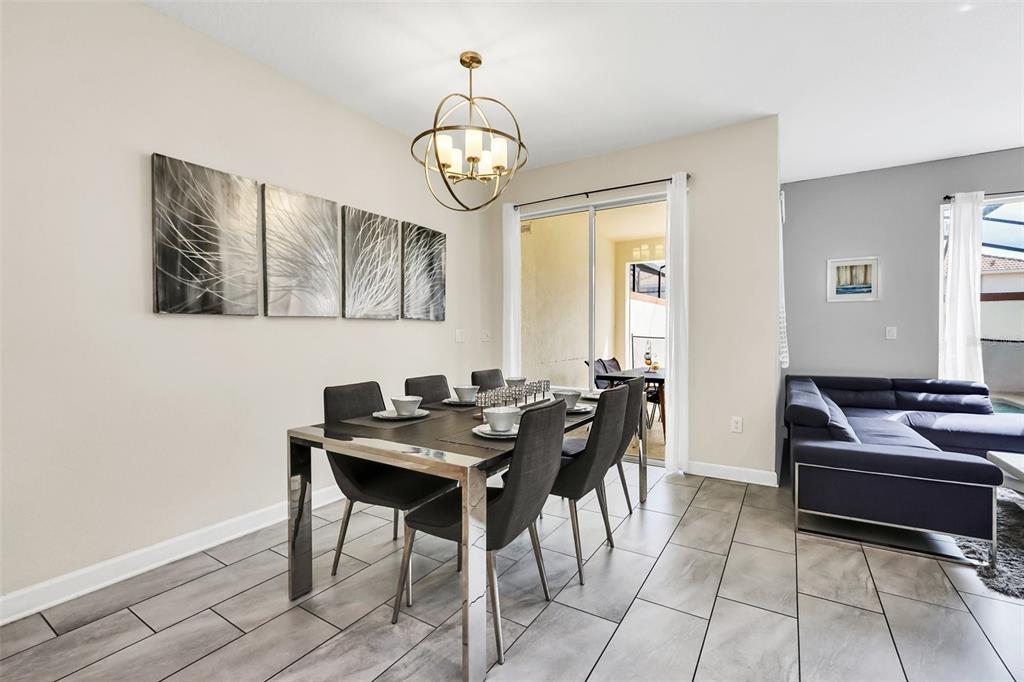 A dining area with a modern chandelier, table, and chairs next to a living room — 1571 PLUNKER DRIVE, DAVENPORT, FL