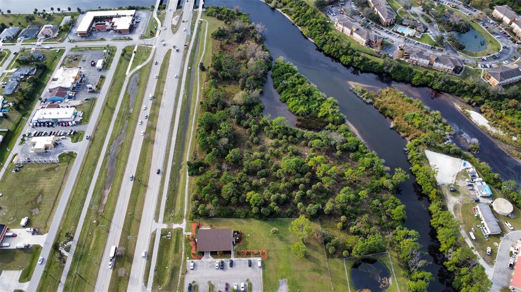 An aerial view shows a wooded lot situated between a multi-lane highway and a river — 14161 S TAMIAMI TRAIL, NORTH PORT, FL