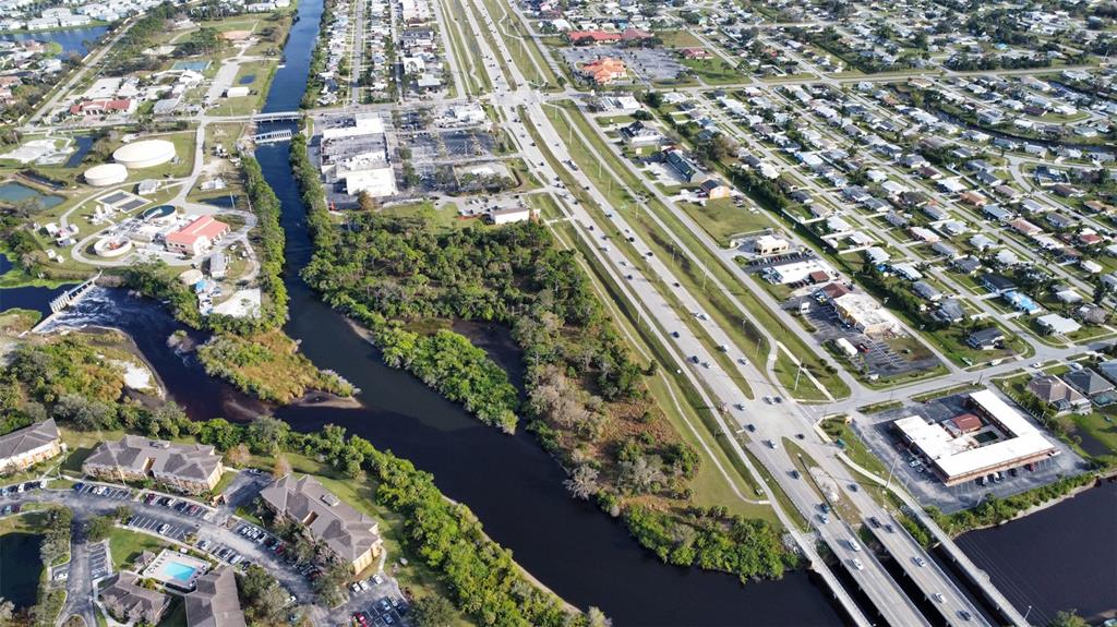 An aerial view shows a river flowing through a suburban area with roads and buildings — 14161 S TAMIAMI TRAIL, NORTH PORT, FL
