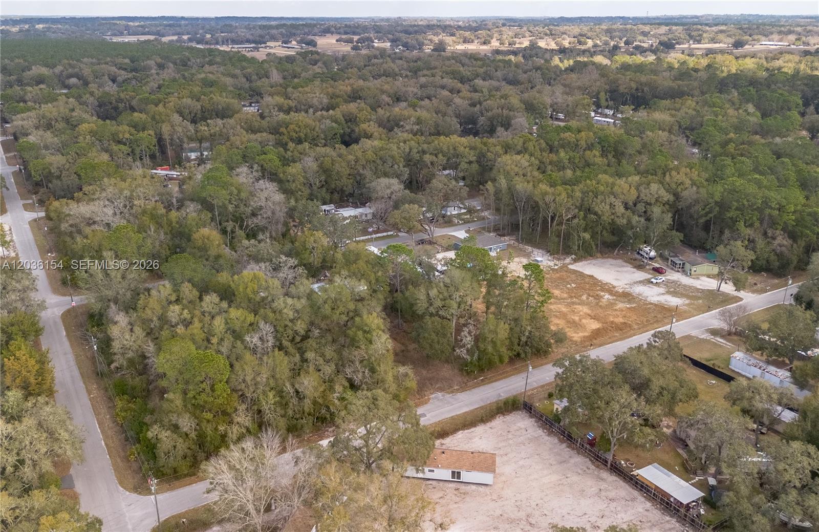 An aerial view shows a rural residential area with scattered houses, cleared lots, and dense trees — NW 13th ST, Ocala FL 34482, OCALA, FL