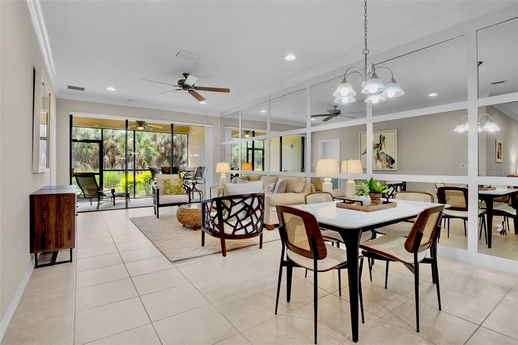 A bright living and dining area features tiled floors, a mirrored wall, and sliding glass doors — 5425 CICERONE STREET UNIT 103, SARASOTA, FL
