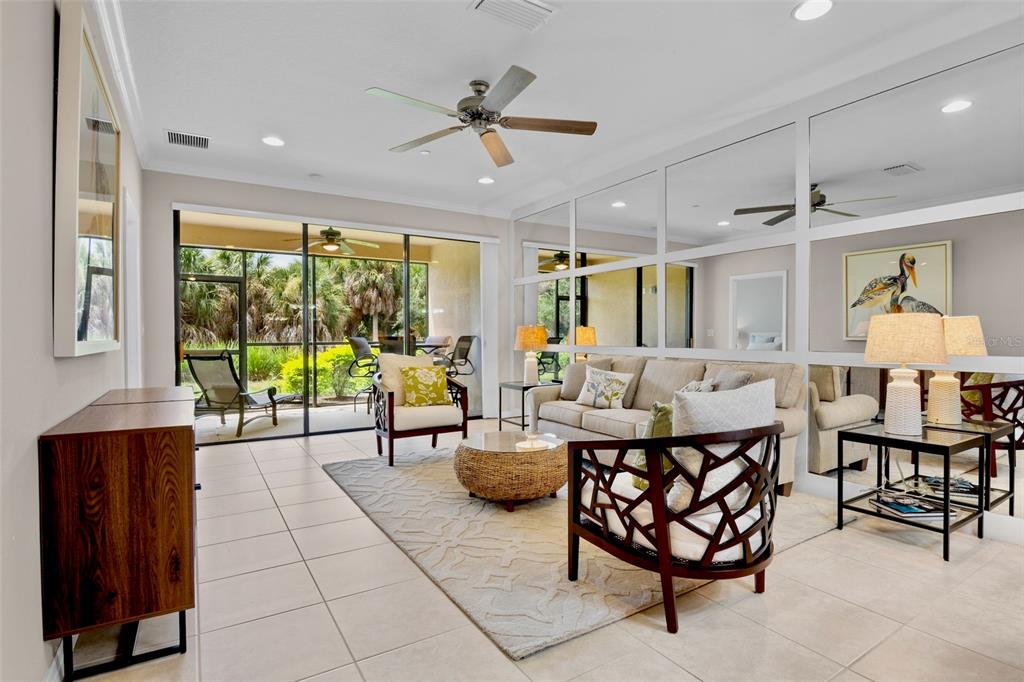 A living room features a mirrored wall, a beige sofa, and sliding doors to a patio — 5425 CICERONE STREET UNIT 103, SARASOTA, FL