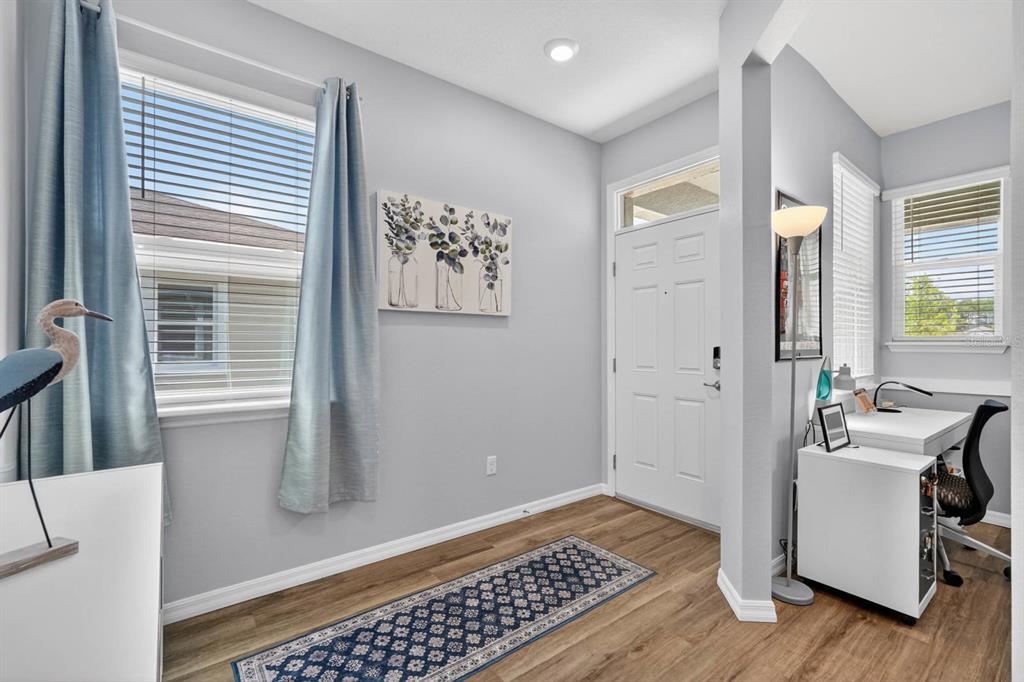 A bright entryway features light gray walls, wood-look flooring, a desk area, and a front door — 2708 KINSALE LANE, ORMOND BEACH, FL