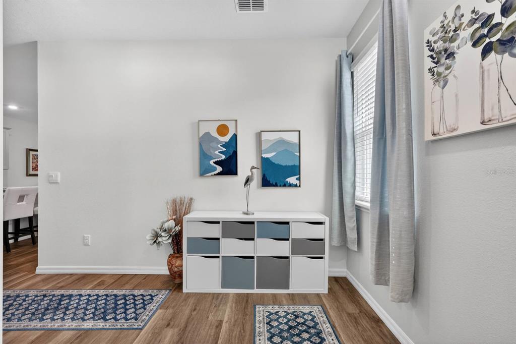 A white storage unit with blue and grey bins sits against a wall with artwork — 2708 KINSALE LANE, ORMOND BEACH, FL