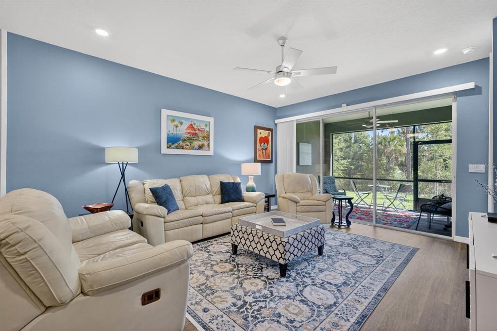 A living room features light blue walls, cream leather furniture, a patterned rug, and sliding doors — 2708 KINSALE LANE, ORMOND BEACH, FL