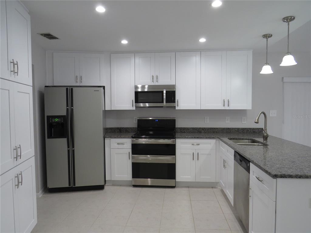 A kitchen features white cabinets, stainless steel appliances, and granite countertops — 4023 PADDLEWHEEL DRIVE, BRANDON, FL