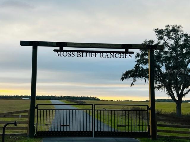 A metal gate with a Moss Bluff Ranches sign stands at the entrance to a field — SE 74TH LANE ROAD UNIT 8-WEST, OCKLAWAHA, FL