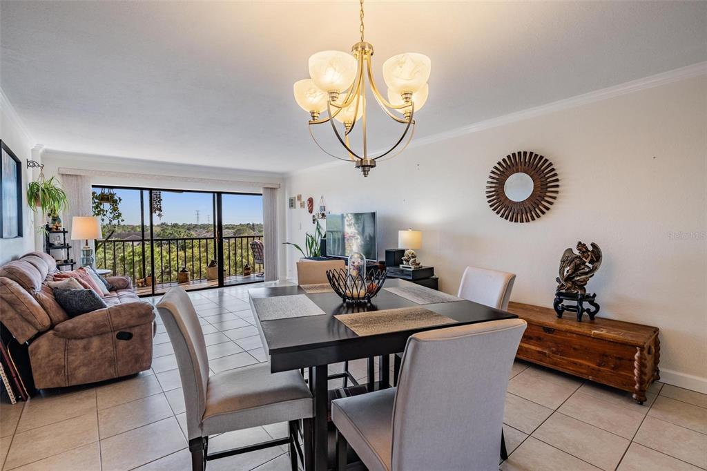 A dining area with a dark table and chairs sits before a balcony with views — 2900 COVE CAY DRIVE UNIT 7B, CLEARWATER, FL