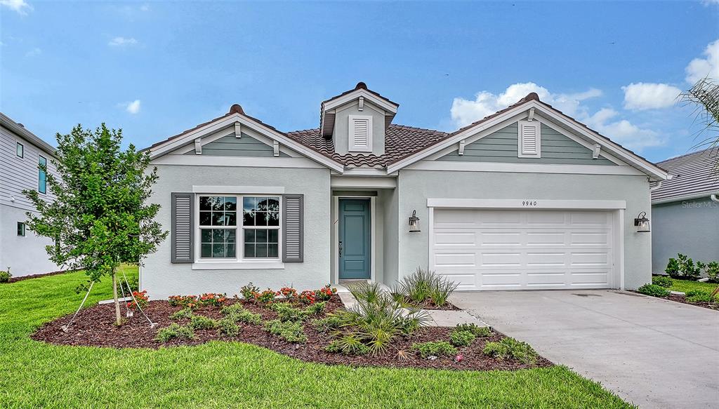 A single-story house with a light-colored stucco exterior, a two-car garage, and a blue door — 9940 CRYSTAL ISLES CIRCLE, SARASOTA, FL