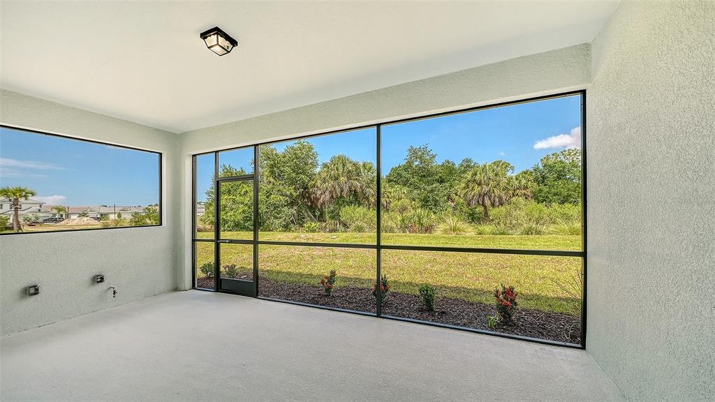 A screened-in patio features a concrete floor, light-colored walls, and views of a grassy yard — 9940 CRYSTAL ISLES CIRCLE, SARASOTA, FL