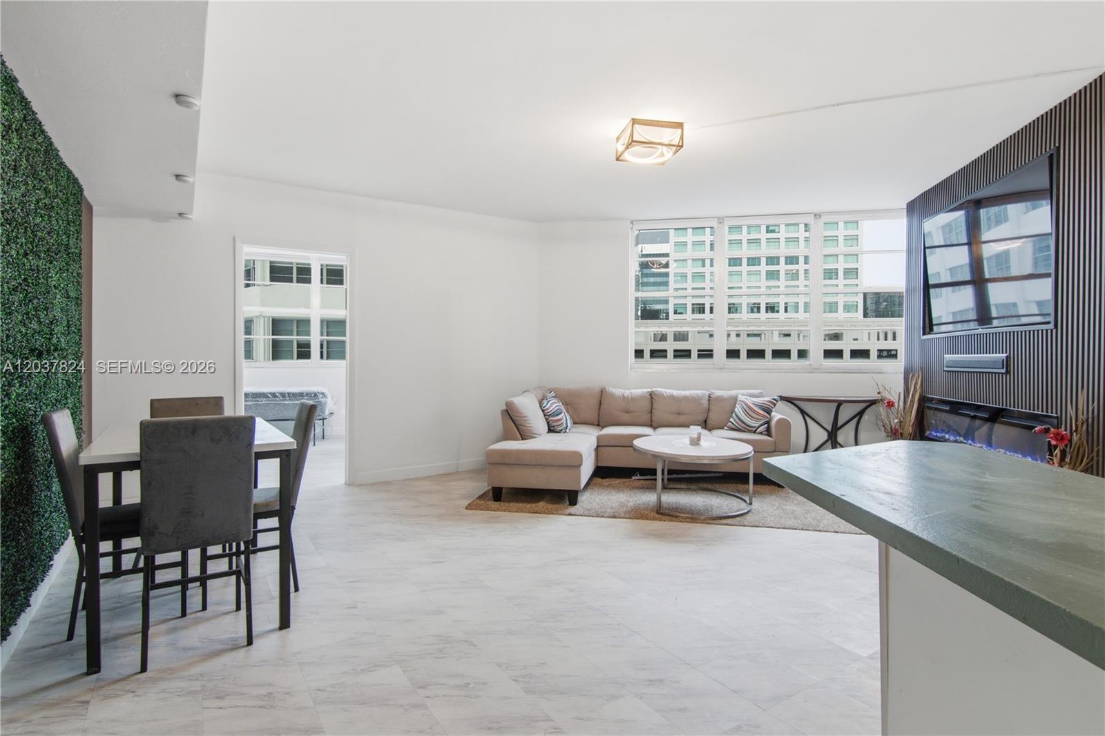 This living and dining area features a green wall, a sectional sofa, and tile flooring — 801 Brickell Bay Dr # 764, Miami FL 33131, MIAMI, FL