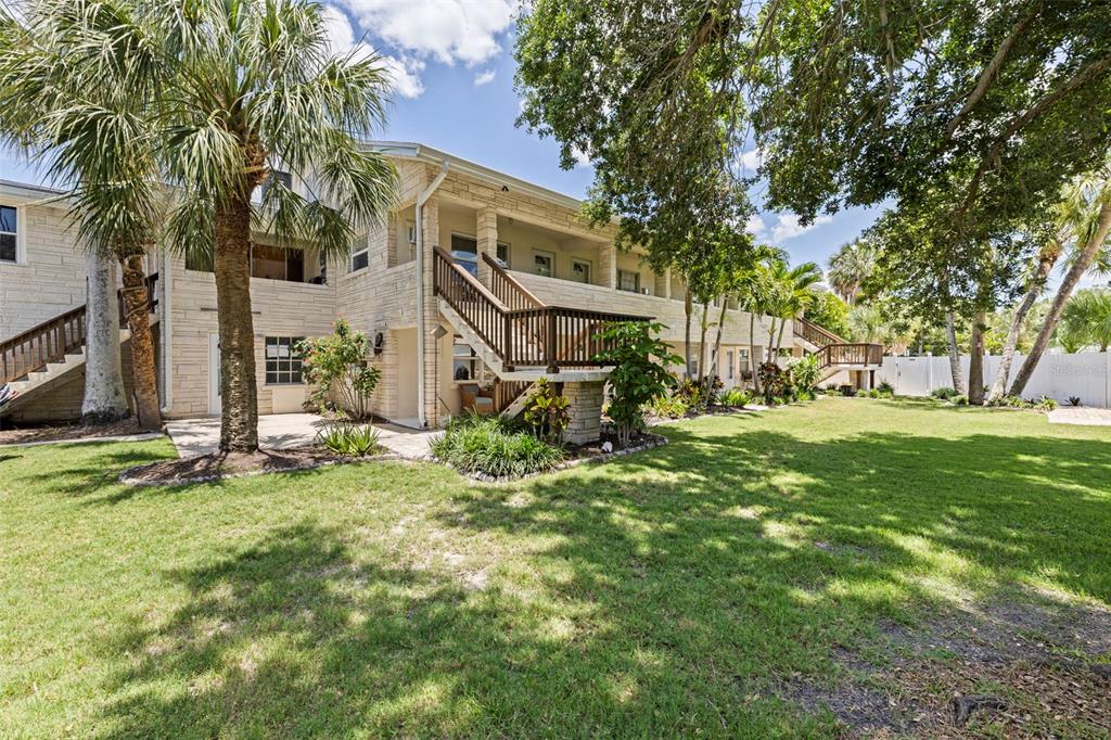A two-story stone building with exterior wooden staircases and a large grassy backyard — 109 16TH AVENUE UNIT 3, INDIAN ROCKS BEACH, FL