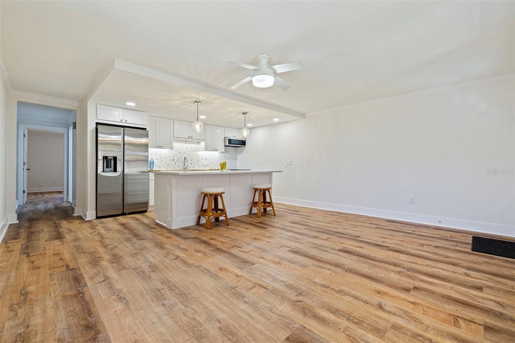 A kitchen with white cabinets and a breakfast bar opens into a spacious living area — 109 16TH AVENUE UNIT 3, INDIAN ROCKS BEACH, FL