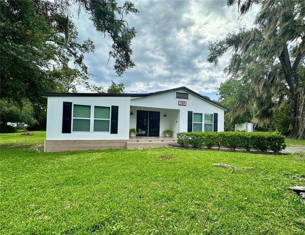 A single-story white house with black shutters and a front porch sits on a lawn — 2505 NE 13TH AVENUE, OCALA, FL