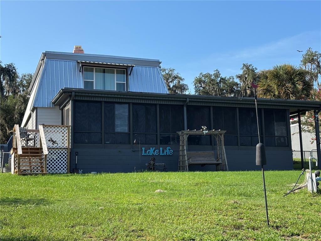 A two-story house with a metal roof and a screened-in porch sits on grass — 120 LITTLE ORANGE LAKE DRIVE, HAWTHORNE, FL