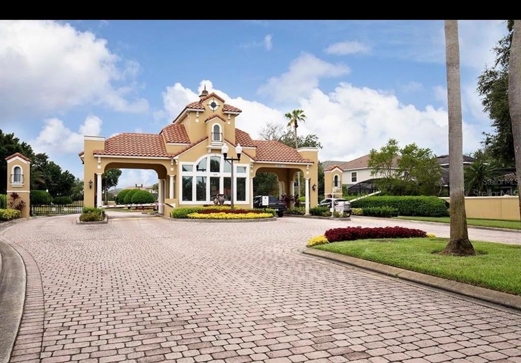 A gated community entrance features a tan stucco guardhouse with a red tile roof — 8242 VIA VERONA, ORLANDO, FL