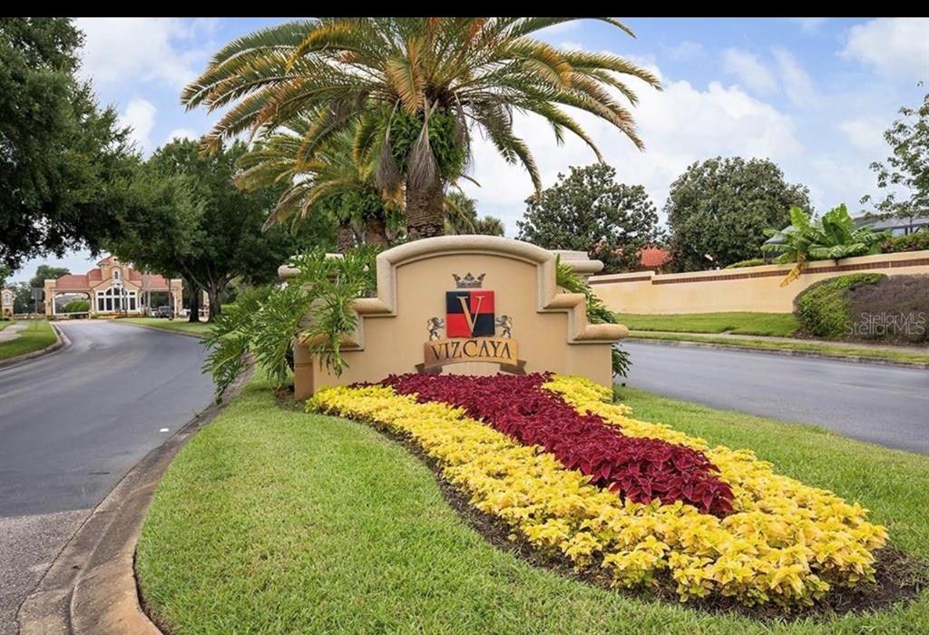 A beige monument sign with the name Vizcaya sits in a landscaped garden bed — 8242 VIA VERONA, ORLANDO, FL