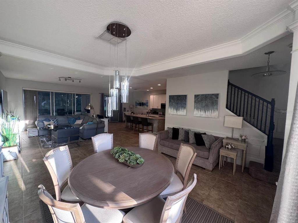 An open-concept living and dining area features tile flooring, a round table, and a staircase — 8242 VIA VERONA, ORLANDO, FL