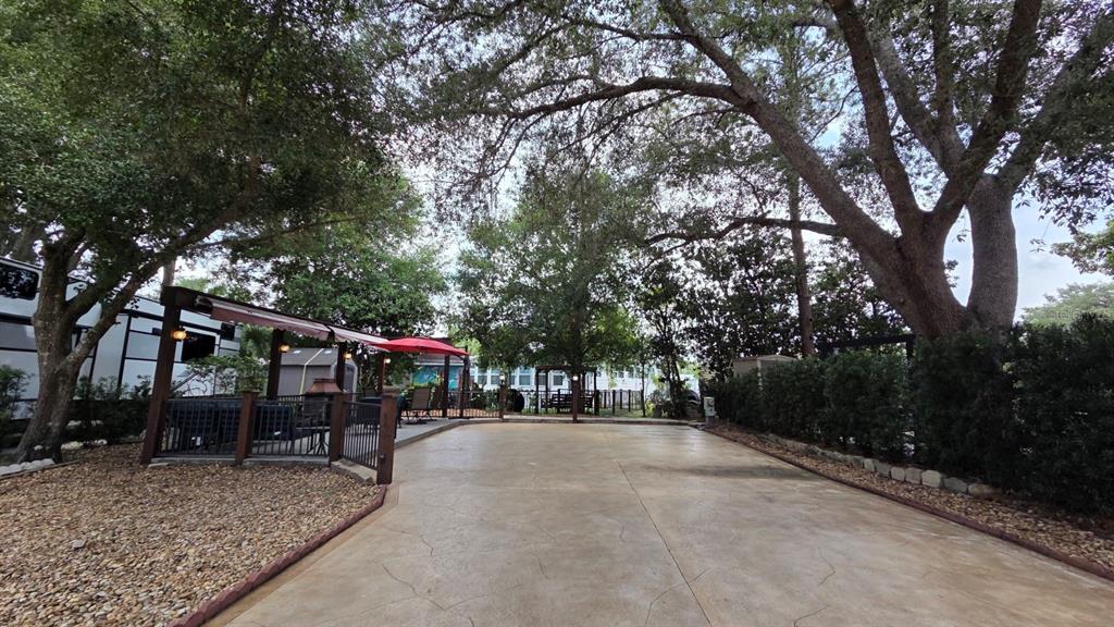 A concrete driveway leads to a shaded outdoor patio area with a red umbrella — 145 HORSESHOE BEND, RIVER RANCH, FL