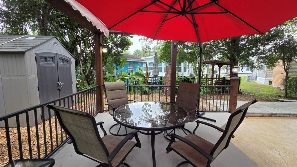 A patio features a glass-topped table, four chairs, and a large red umbrella — 145 HORSESHOE BEND, RIVER RANCH, FL