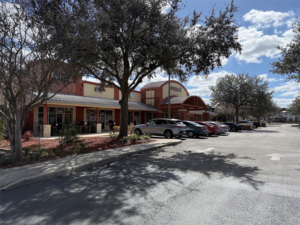 A commercial strip mall building with a parking lot and trees under a blue sky — 2611 SW 19TH AVENUE ROAD UNIT 700, OCALA, FL