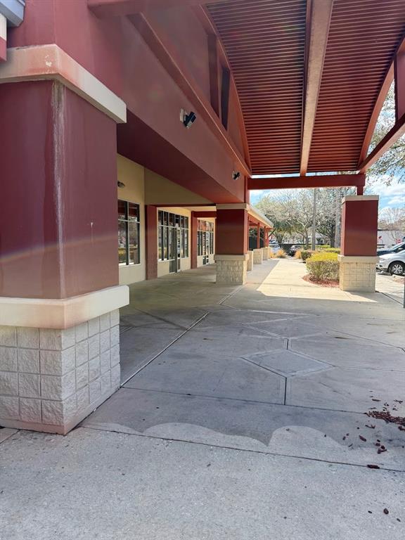 A covered concrete walkway runs along the exterior of a commercial building with red pillars — 2611 SW 19TH AVENUE ROAD UNIT 700, OCALA, FL
