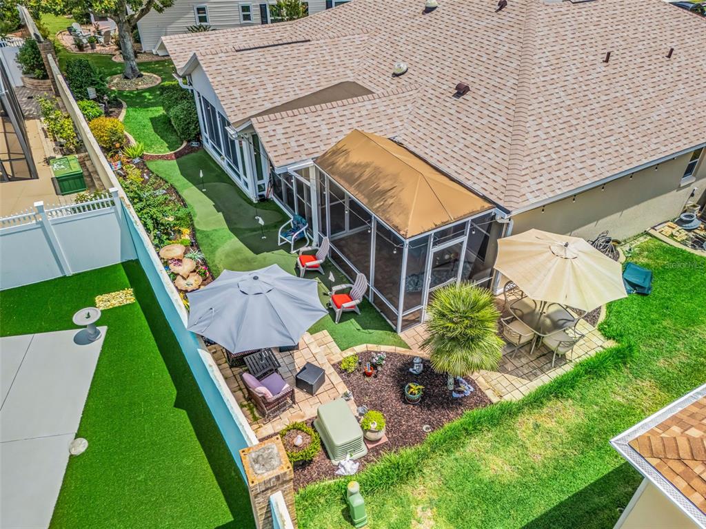 An aerial view of a backyard featuring a putting green, screened patio, and paved seating area — 17770 SE 85TH ELLERBE AVENUE, THE VILLAGES, FL